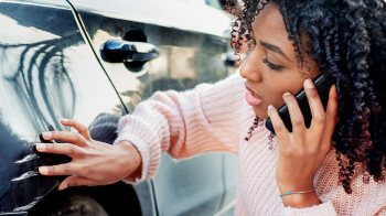 On the phone with a State Farm agent, a woman inspects her car’s exterior.