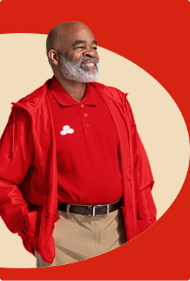 A bearded State Farm agent in red shirt and red pullover jacket smiles.
